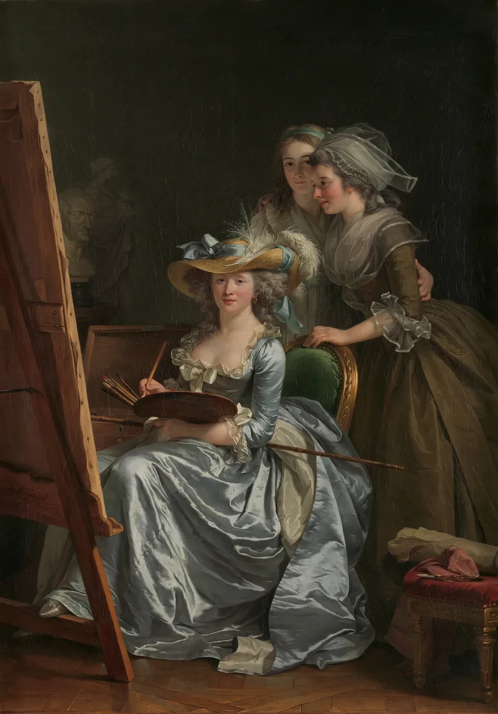 Adélaïde Labille-Guiard assise devant son chevalet, palette et pinceaux à la main, robe de satin bleu et chapeau à plumes, deux jeunes élèves debout derrière elle