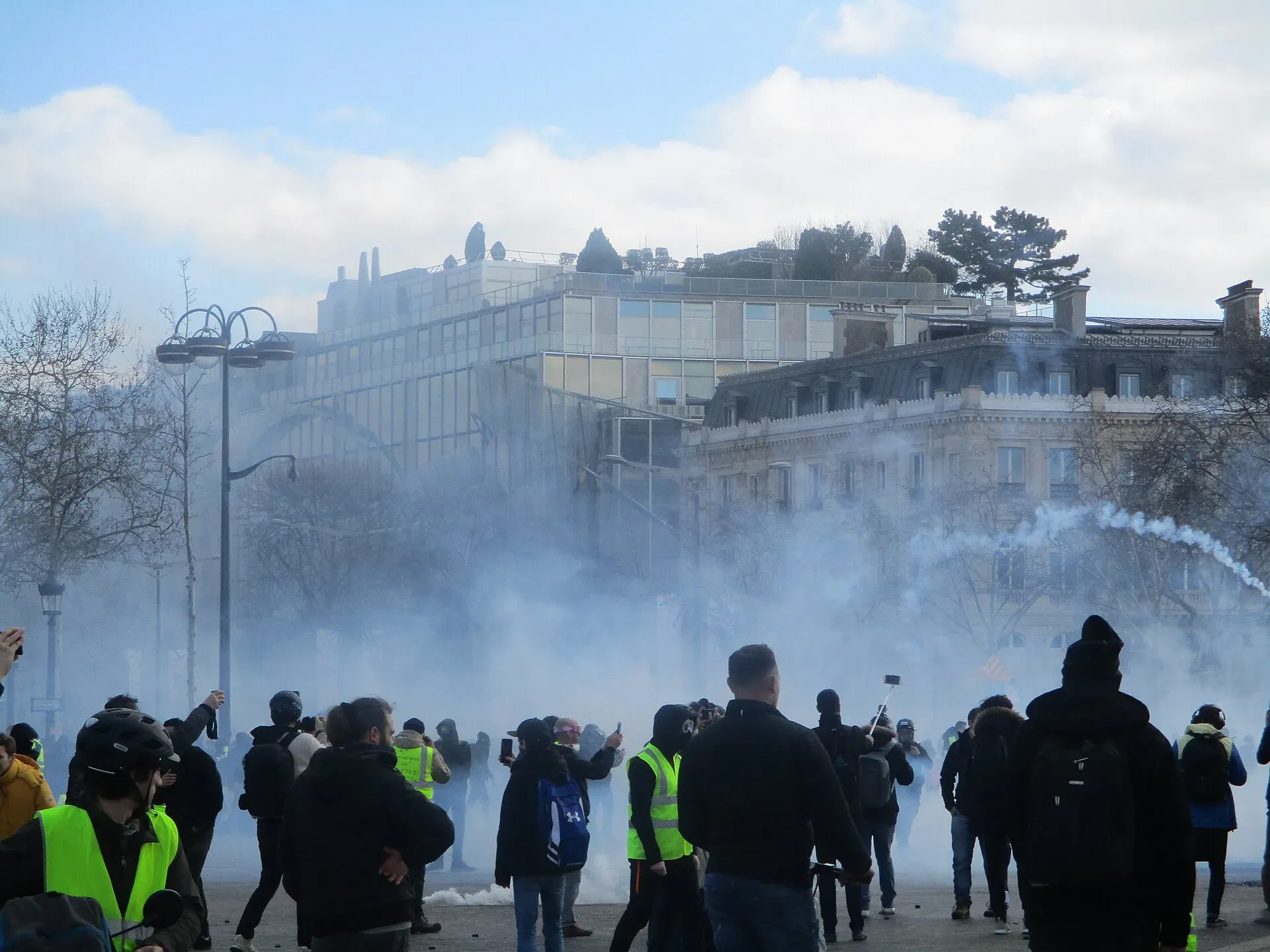 Nuage de gaz lacrymogène en haut des Champs-Élysées, une grenade encore en l’air au-dessus des manifestants