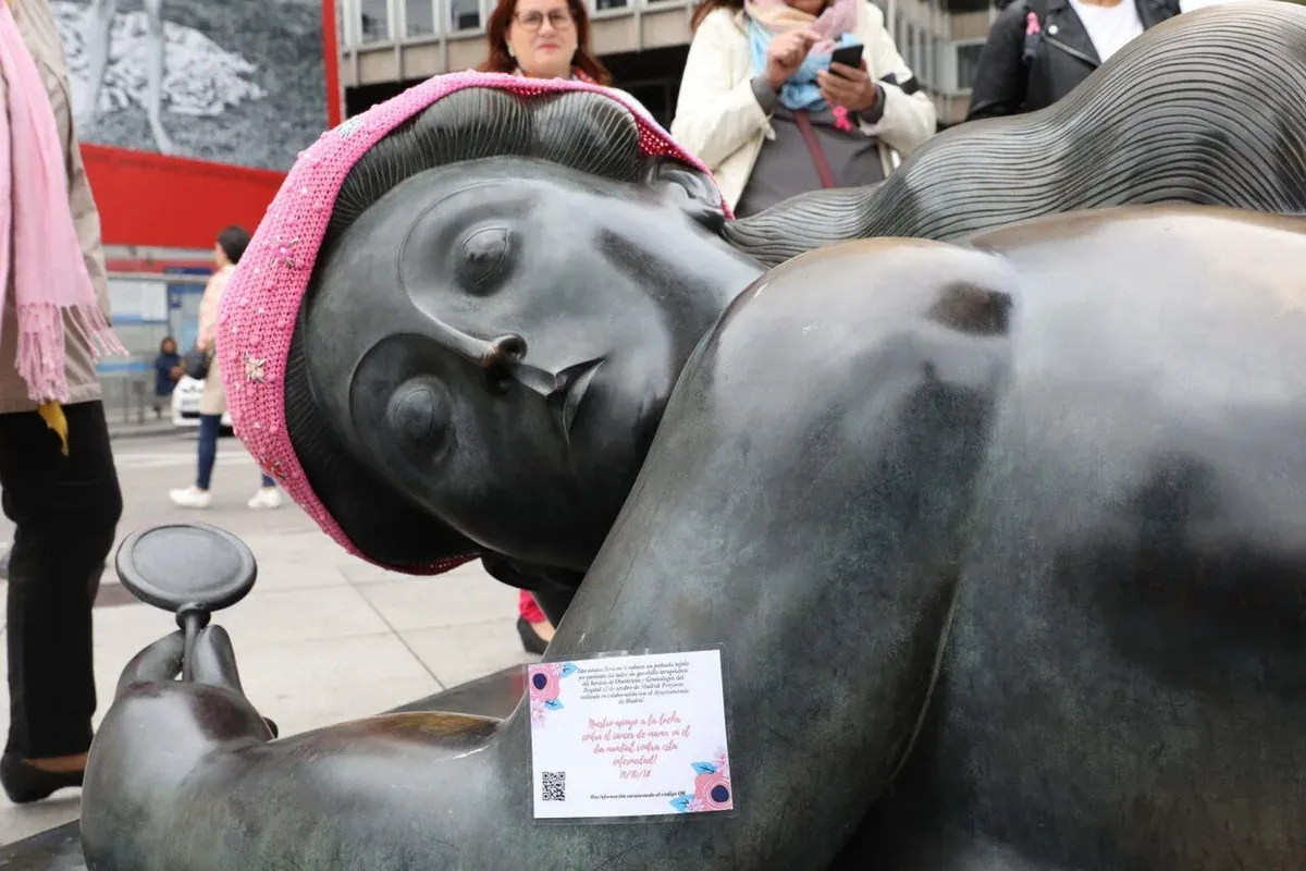 Sculpture en bronze de Botero représentant une femme allongée, coiffée d’un foulard rose au crochet, sur une place de Madrid