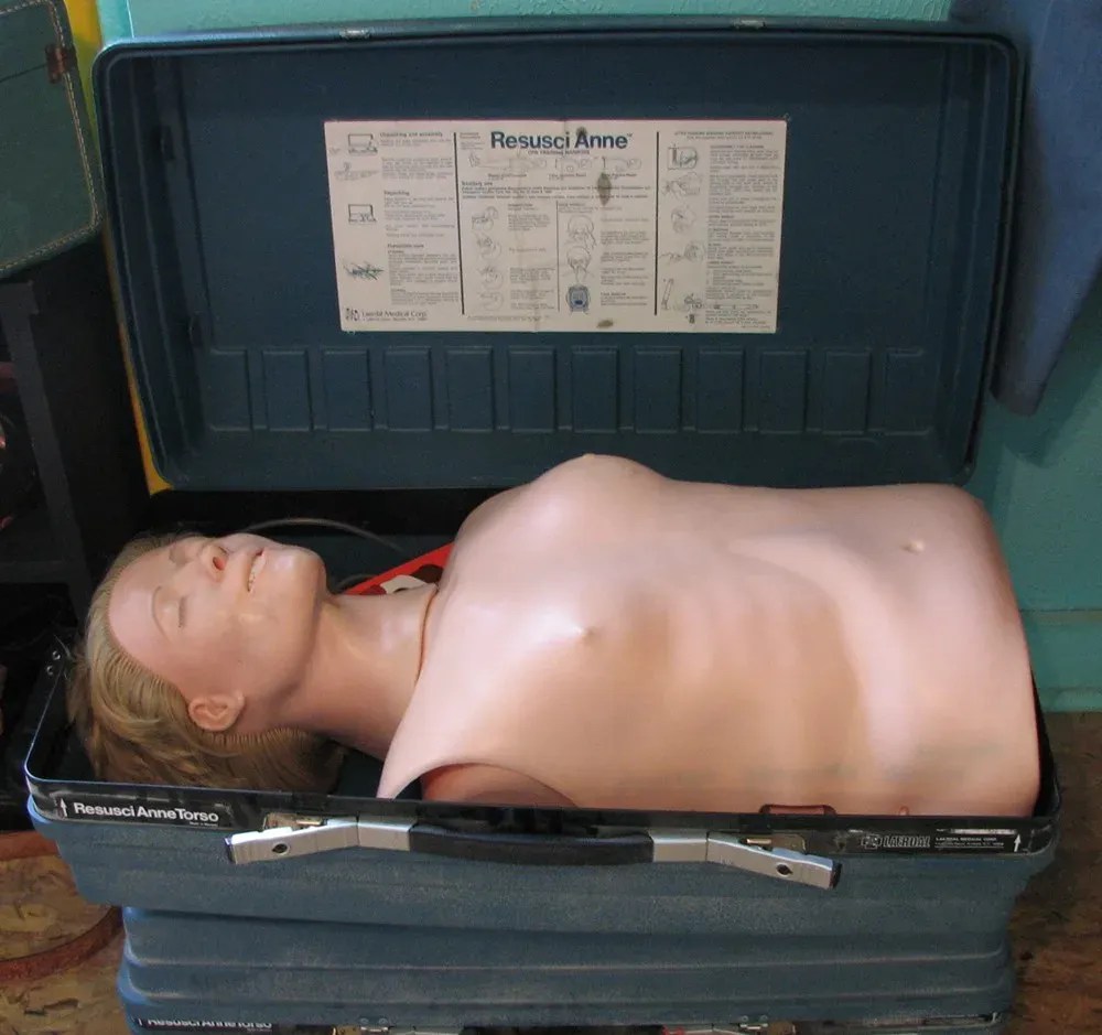 Mannequin de secourisme Resusci Anne, torse nu et plat, allongé dans sa mallette de transport ouverte